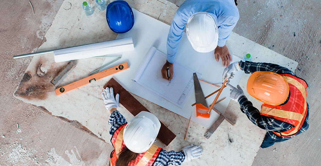 3 construction workers looking at a blueprint